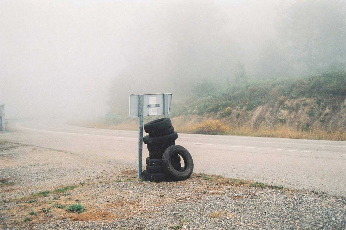 Un montón de neumáticos al lado de una carretera con niebla